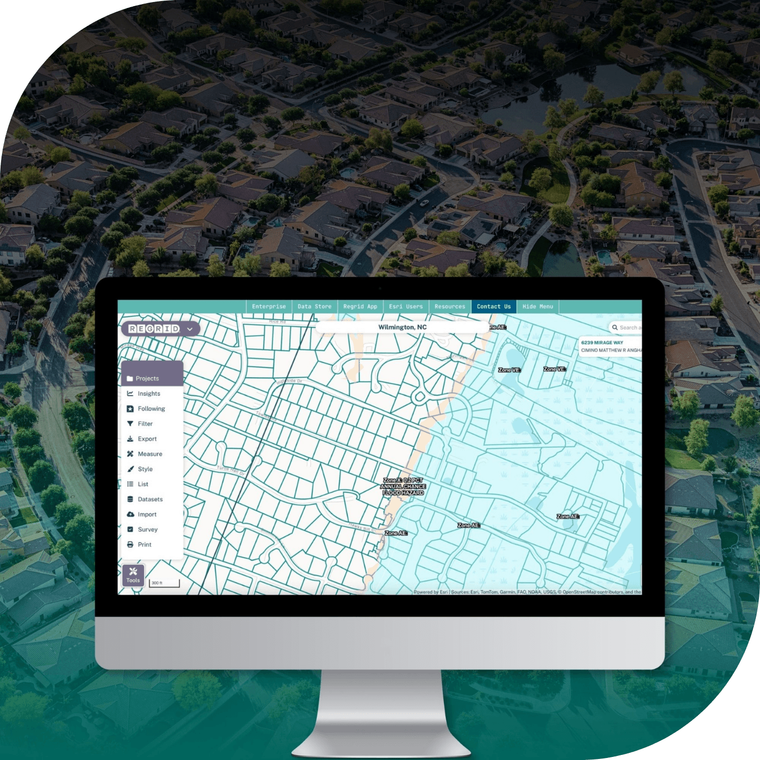 A desktop monitor displaying an aerial map interface with street grids, labels, and a left legend panel, shown over a background aerial neighborhood view. A desktop monitor displaying an aerial map interface with street grids, labels, and a left legend panel, shown over a background aerial neighborhood view.