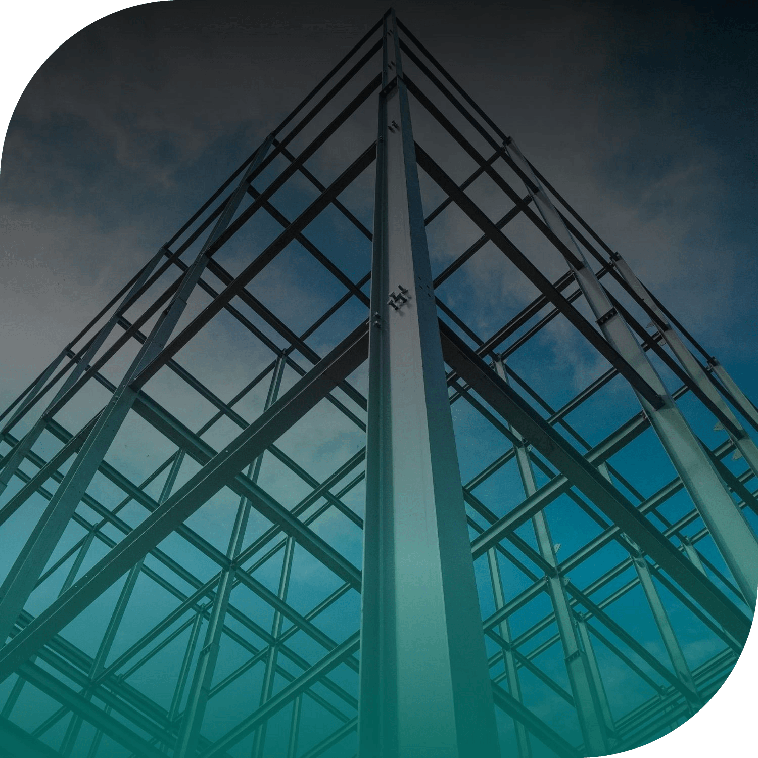Low-angle view of a tall steel building structure with crisscross beams and a central vertical column, seen against a cloudy blue-gray sky.